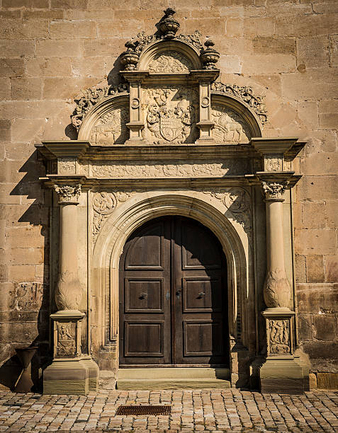 Renaissance gate with wooden door and elaborate architectural stone  adornments. Vertical orientation.