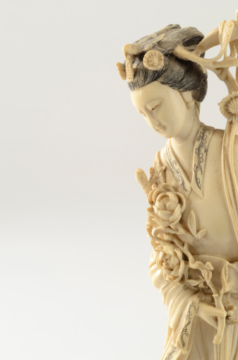 19th century Chinese carved ivory woman figurine looking left with copy space and on a white background.