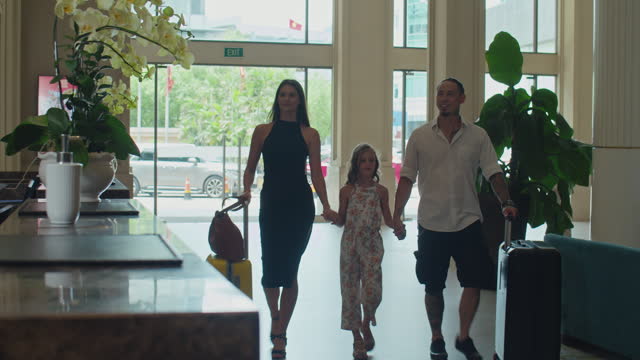Family with Baggage Walking towards Reception Area in Hotel