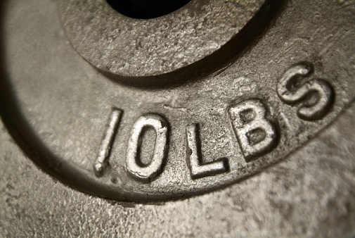 Close up image of a ten pound weight. The lighting creates a nice texture on the metal. The words 10 LBS stand out.