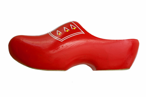 A tradional Dutch wooden shoe, isolated on white. This used clog is handpainted in red and decorated with white and yellow on the top.