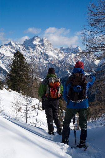 Walkers admire the Sorapis massiff while snowshoeing in the Italian Dolomites