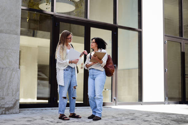 istock to female students chatting and laughing outdoors after classes in university. 1715554624