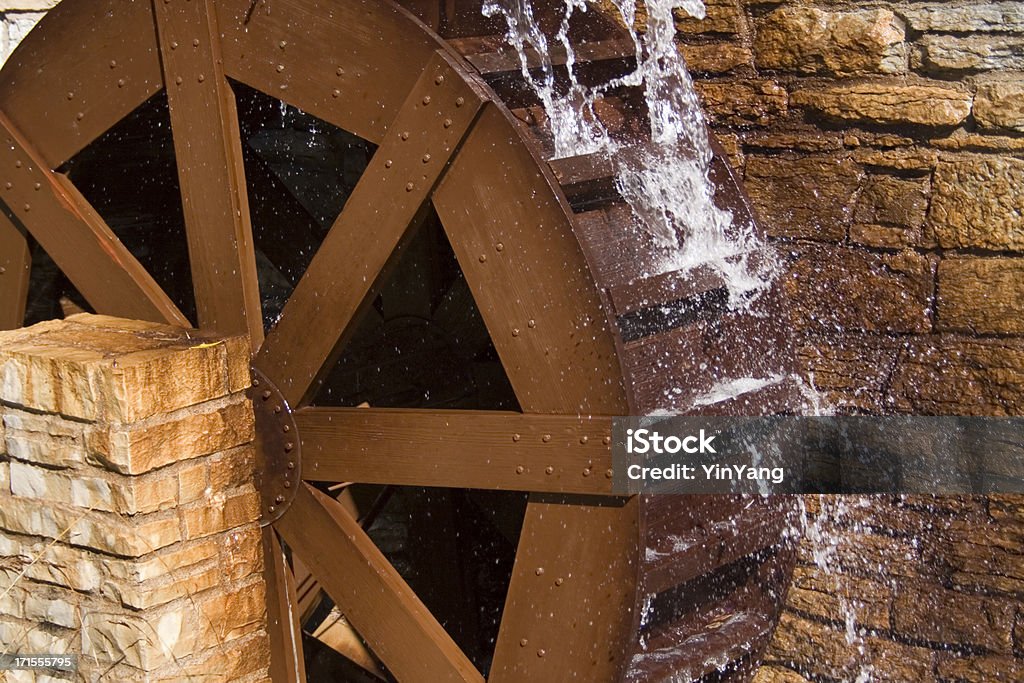 Water Wheel or Watermill Turbine Grinding, Turning, and Generating Power A wooden water wheel or watermill turbine milling, grinding, turning, and generating power, perhaps as a traditional alternative energy source. Positioned against the stone wall of a cottage building exterior, located in St. Paul, Minnesota, USA. Watermill Stock Photo