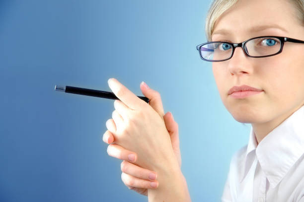 Businesswoman holding a pen and face turned to viewer.