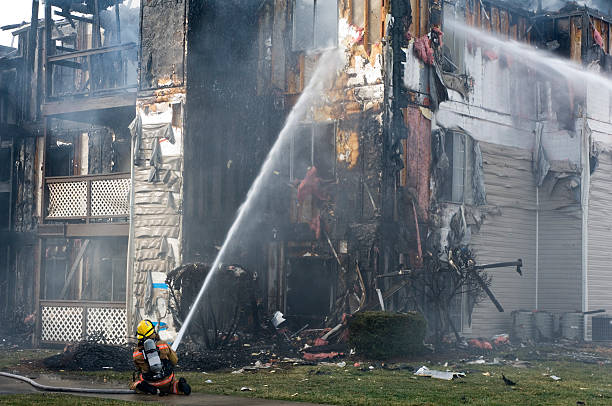 istock Fireman Spraying water on burning Apartment Building Destroyed 171556178