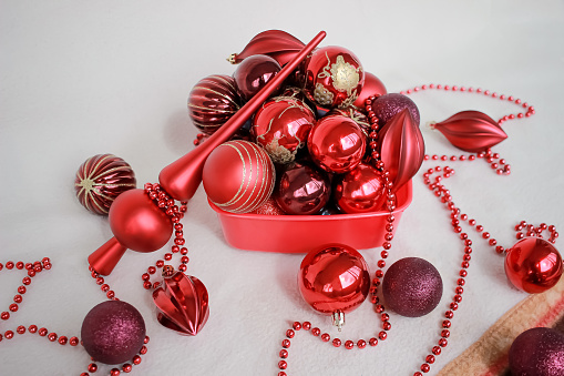 red toys, ornaments, balls, beads and a top for the Christmas tree lie in a box on a white blanket. preparation for Christmas and New Year concept