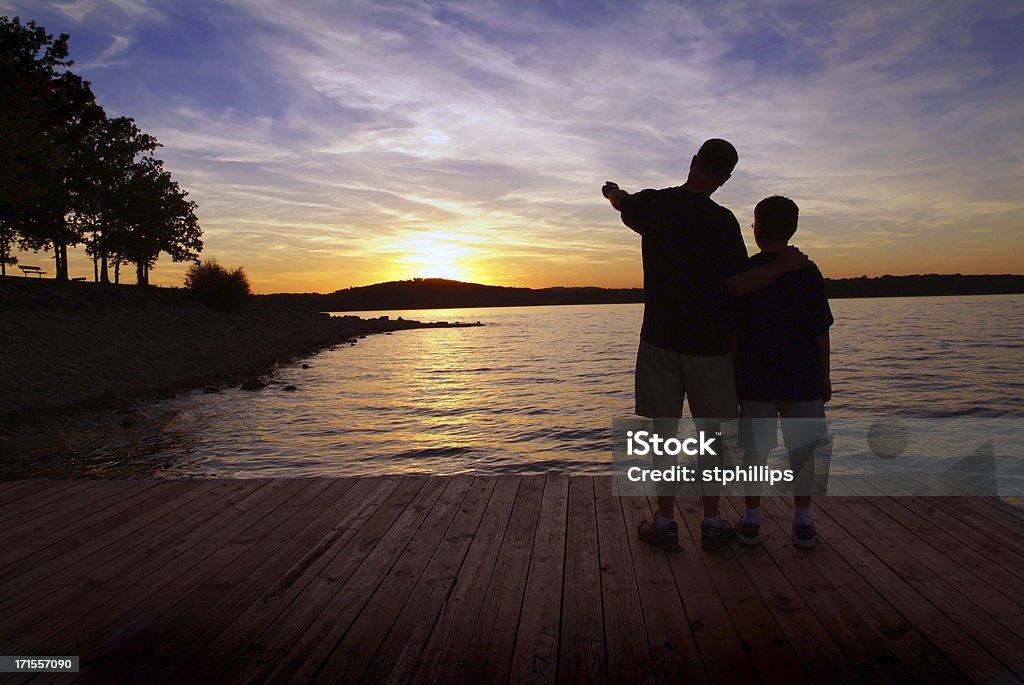 Ojciec i syn stojąc na łódkę dok o zachodzie słońca - Zbiór zdjęć royalty-free (Ojciec)