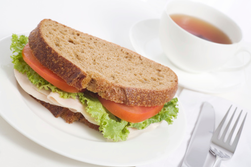 A turkey sandwich with lettuce and tomato on wheat bread