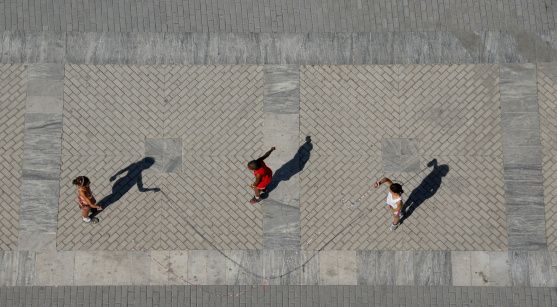 Shot of three kids skipping taken from the room of a very high building!