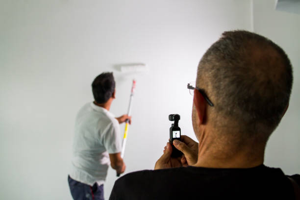 istock Rear View Of Man Filming Painter While Painting The Wall 1715595049