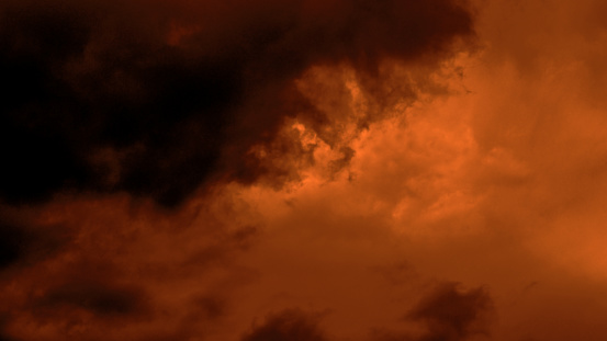 Dark brown and orange sunset stormy sky with fluffy clouds. Dramatic moody sky. Halloween cloudscape background concept.