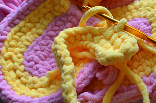crocheted pattern, light pink and yellow soft yarn, crochet hook, hobby inspiration
