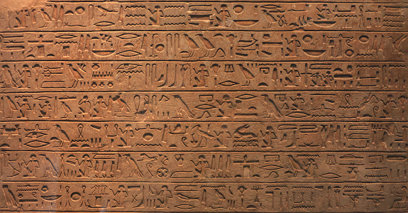 Historical Egyptian symbols, drawings and symbols in the form of text on the wall. Ancient Egyptian writings, hieroglyphs and signs on stone slab close-up.