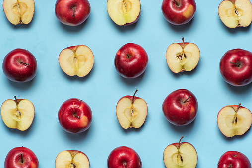 Fresh red apples with seeds on light blue background. Fruits pattern, top view