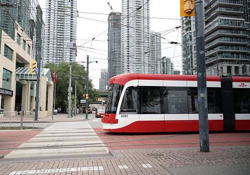 Toronto, Canada - August 25, 2023: A TTC 509 Harbourfront streetcar travels along Queens Quay West. Looking north on Lower Spadina Avenue in the Harbourfront-CityPlace neighbourhood. Overcast summer morning.