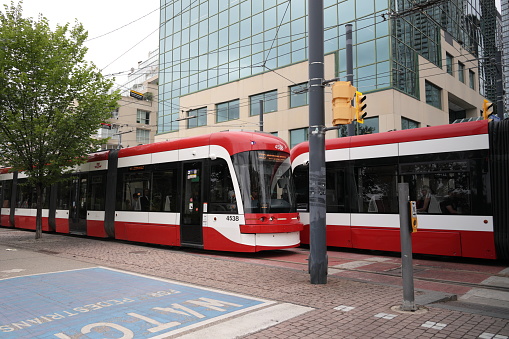 Toronto, Canada - August 25, 2023: TTC 509 Harbourfront streetcars head in opposite direction along Queens Quay West near Lower Spadina Avenue. View from the Martin Goodman Trail, part of the Trans Canada Trail by Lake Ontario.