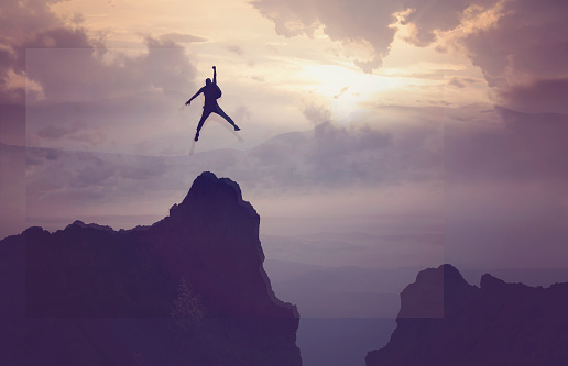 Businessman Jumping on Mountain Peak