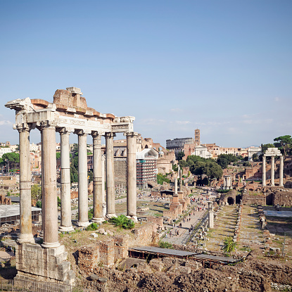 People walking among the awe inspiring ancient ruins of the Roman Forum in the city centre of Rome.