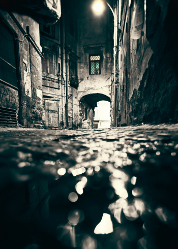 Dark alley in old town. Reflected in puddle.