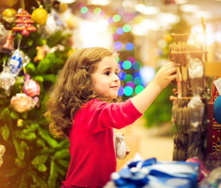 Little girl choosing Christmas gifts in a shop