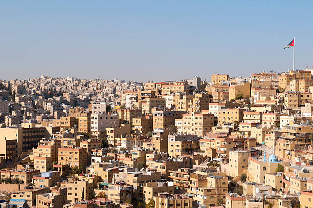 Buildings and skyline of Amman, Jordan. The Jordanian flag is on the upper right. A mosque on the lower right (blue dome).