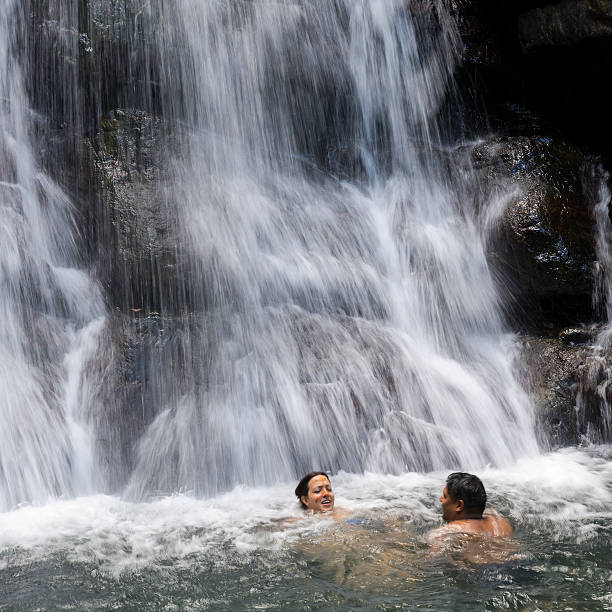 Couple swimming at La Mina Falls in El Yunque National Forest in Puerto Rico A man and woman on honeymoon, swimming at La Mina Falls at El Yunque National Forest in Puerto Rico. el yunque rainforest stock pictures, royalty-free photos & images