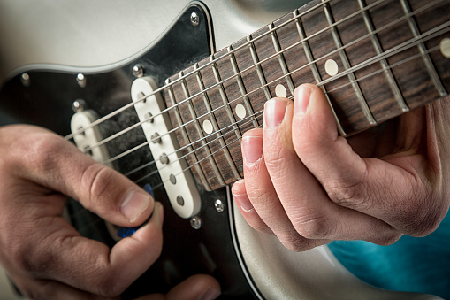 Electric Guitar Closeup with player bending strings, shallow depth of field, effects added