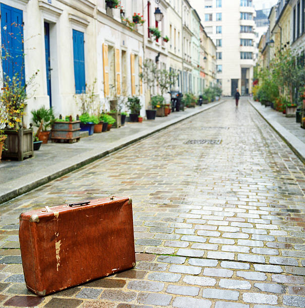 Paris, France. Focus on the suitcase. A blurred silhuette can be seen leaving. Scan from 120-Portra 400