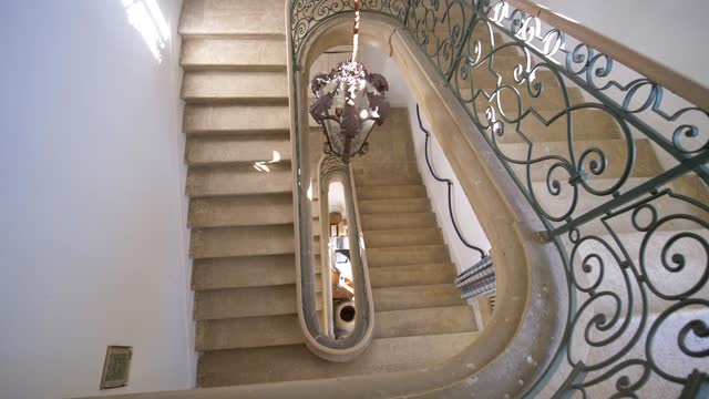 Slow revealing shot of a luxury stone staircase with intricate metal railings