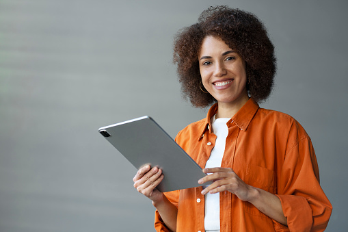 Beautiful smiling African woman holding digital tablet, smiling looking at camera. People Business Technology