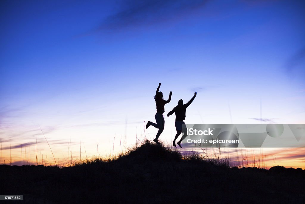 Deux Silhouettes d'hommes de sauter sur la plage au coucher du soleil - Photo de 20-24 ans libre de droits