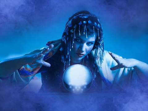 Mysterious fortune teller gesturing at crystal ball