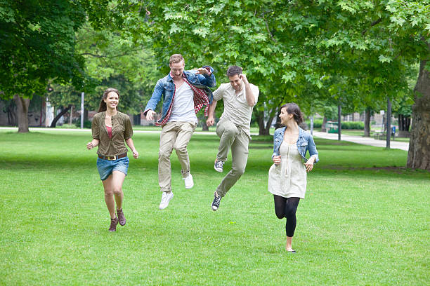 gruppe von jungen menschen laufen und springen im park - 20s berlin germany heterosexual couple boyfriend stock-fotos und bilder