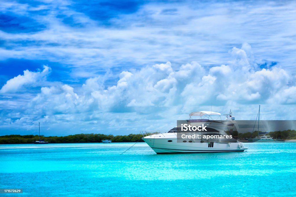 Luxury yacht anchored in a Tropical island turquoise beach Luxury yacht anchored in a Tropical island turquoise beach in Los Roques islands, Venezuela. Boats, sailboats and yachts anchored in a Caribbean island. Travel and leisure related images for vacations in the Caribbean. Image taken at Los Roques, Venezuela. Los Roques is an archipelago or group of small islands located at 80 miles north of the Venezuelan coastline and a very popular destination for leisure, diving, kite surfing and all king of water activities. Los Roques and the beauty of the turquoise coastal beaches of Venezuela are almost indistinguishable from those of the Bahamas, Fiji, Bora Bora, French Polynesia, Malau, Hawaii, Cancun, Costa Rica, Florida, Maldives, Cuba, Puerto Rico, Honduras, or other tropical areas. Yacht Stock Photo