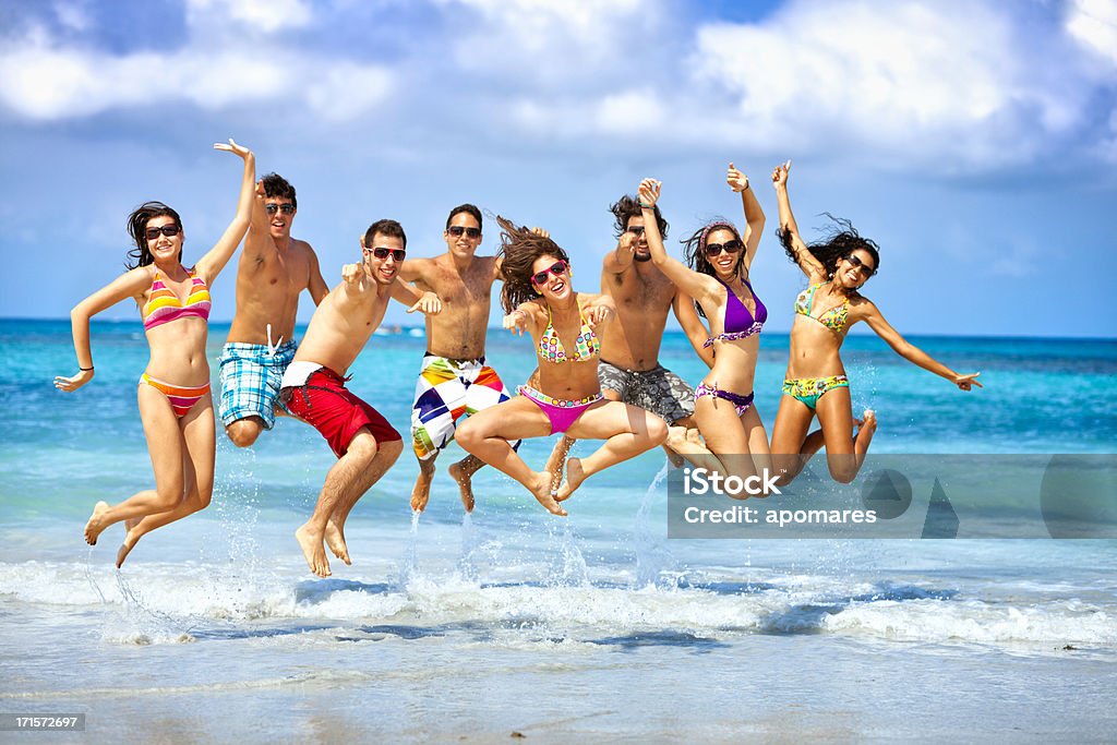Feliz grupo de jovens pulando em uma festa de praia - Foto de stock de Festa na praia royalty-free