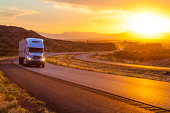 18-wheeler tractor-trailer truck on interstate highway at sunset