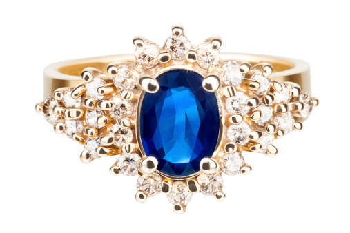 Emerald with Tanzanite ring on dark blue velvet bag. Collection of natural gemstones accessories. Studio shot