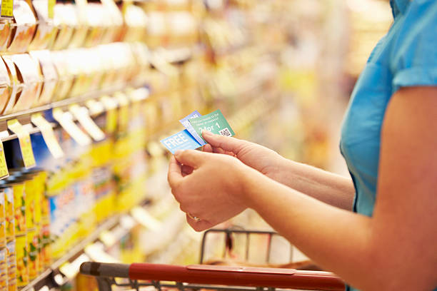 A woman checking her coupons in the store Woman In Grocery Aisle Of Supermarket With Coupons coupon stock pictures, royalty-free photos & images