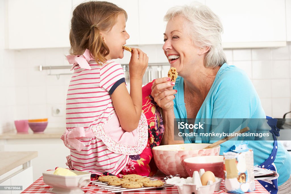 Grandma and Granddaughter laugh and bake cookies Grandmother And Granddaughter Baking In Kitchen Smiling And Laughing At Each Other. Grandmother Stock Photo