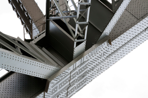 Closeup low angle view of gigantic steel beams supporting bridge structure, Harbour bridge Sydney Australia, against white background, full frame horizontal composition with copy space