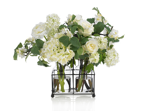 A beautifully designed arrangement of flowers in two small glass vases with a wire holder. It contains roses, hydrangeas and apple blossoms. Shot against a bright white background. There is a path which may be used to delete the reflection if desired. Extremely high quality faux flowers.