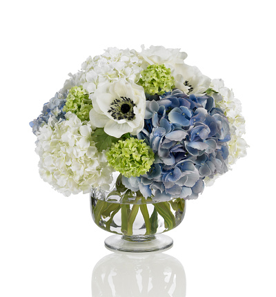 A bouquet made with blue and white hydrangeas with white poppies in a footed glass vase. Shot against a bright white background. There is a path which may be used to delete the reflection if desired. Extremely high quality faux flowers.