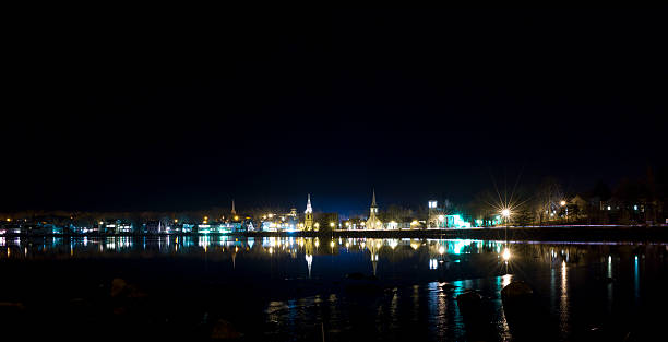 Mahone Bay Nova Scotia Reflection at Night. The main street of Mahone Bay Nova Scotia reflects in the bay in this night time photograph. mahone bay water beach night stock pictures, royalty-free photos & images