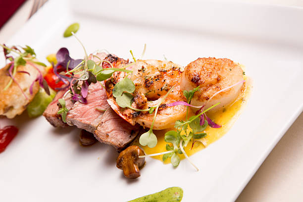 Medium Rare Sliced Steak, Shrimp and Scallops with greens on top.