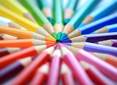 LONG WOODEN PENCILS OF VARIOUS COLORS, ON LIGHT WOODEN TABLE. HORIZONTAL PHOTOGRAPHY. COLOR.