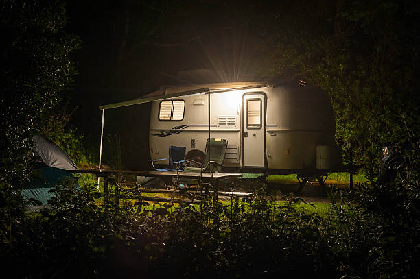 caravana tráiler brillante en el bosque camp el hotel por la noche - caravana tráiler de vehículos fotografías e imágenes de stock