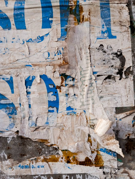 Weathered torn ads poster glued to a concrete wall.