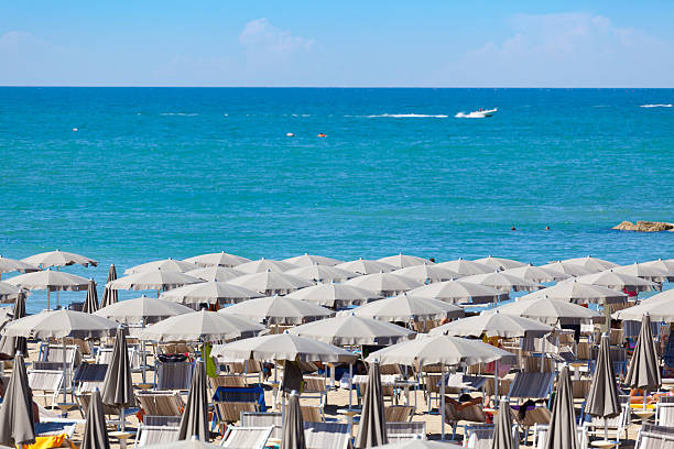 Typical Beach at the Riviera Romagnola long rows of beach umbrellas and beds in Rimini, Emilia RomagnaOTHER BEACH SCENES FROM ITALY: rimini stock pictures, royalty-free photos & images