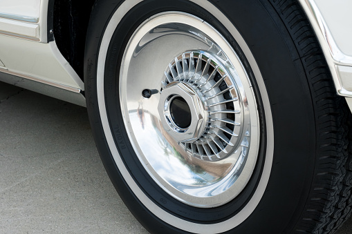 Vintage allow wheel on classic luxury car with white wall tires.